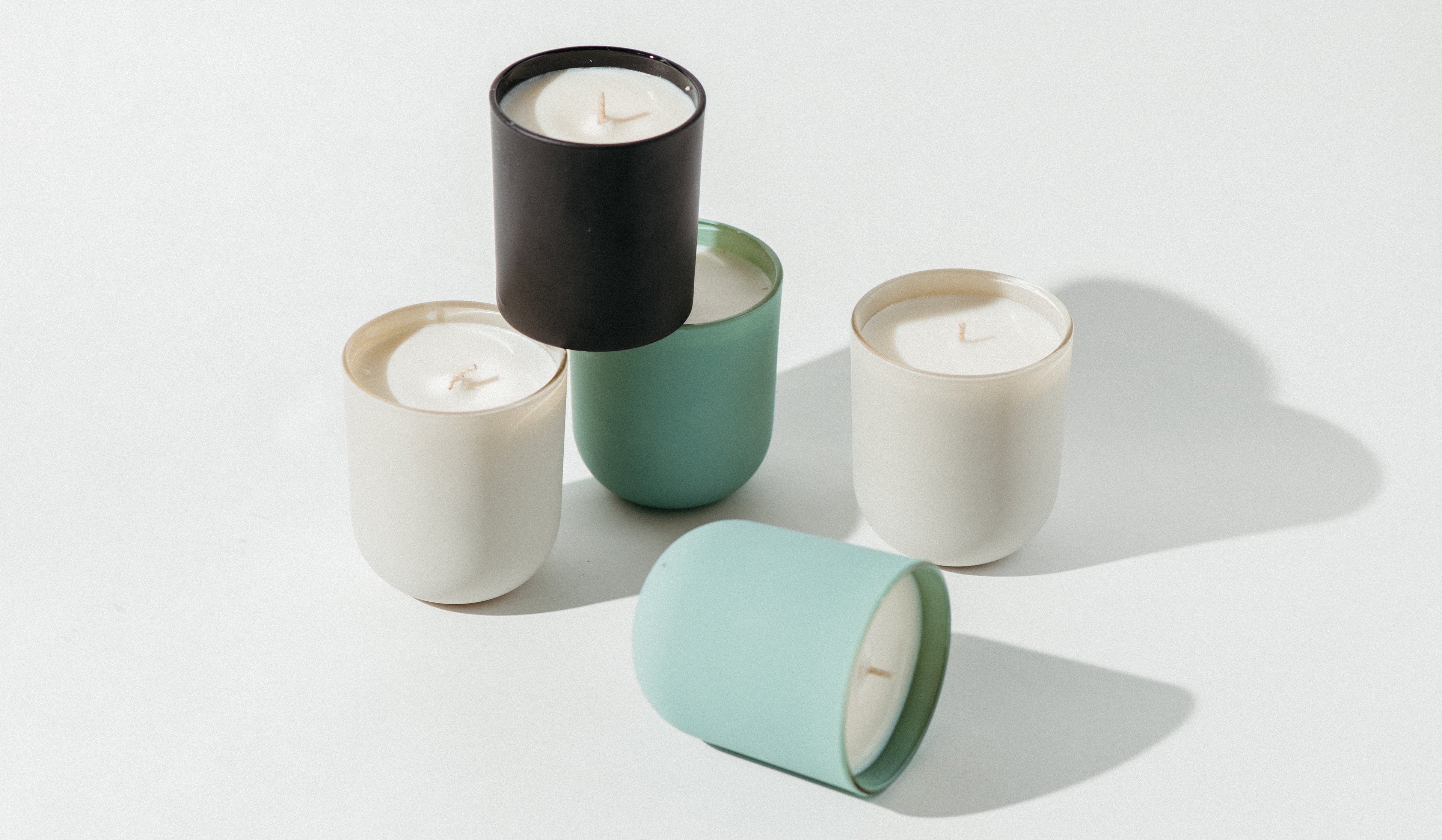 Five candles in various colored containers on a light background